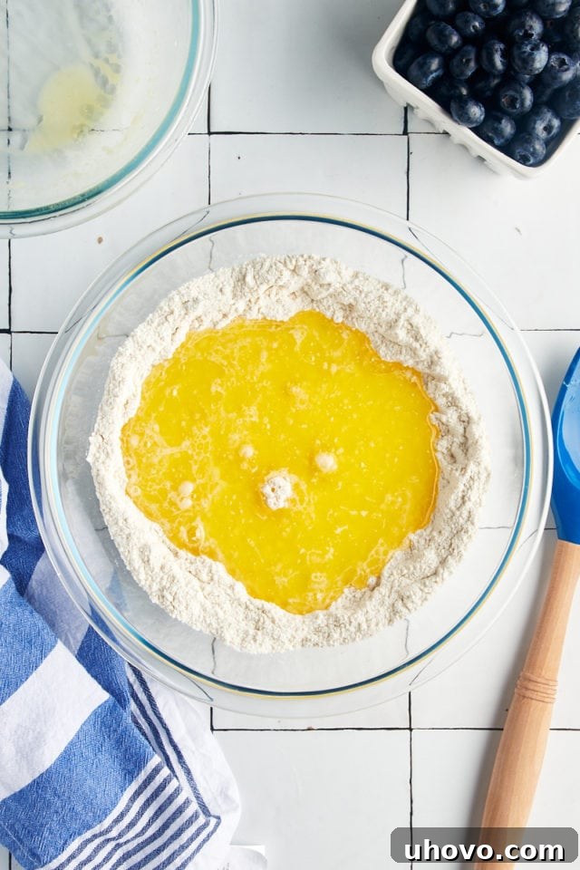 Wet ingredients poured into a well of dry ingredients in a mixing bowl.