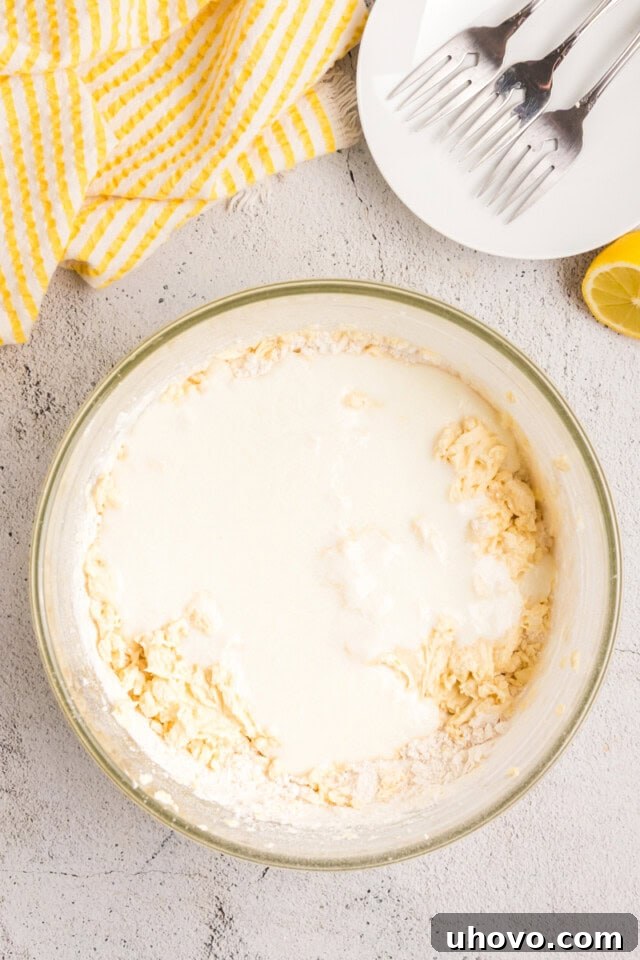 Overhead view of the milk and lemon juice mixture being added alternately with dry ingredients to the cake batter.