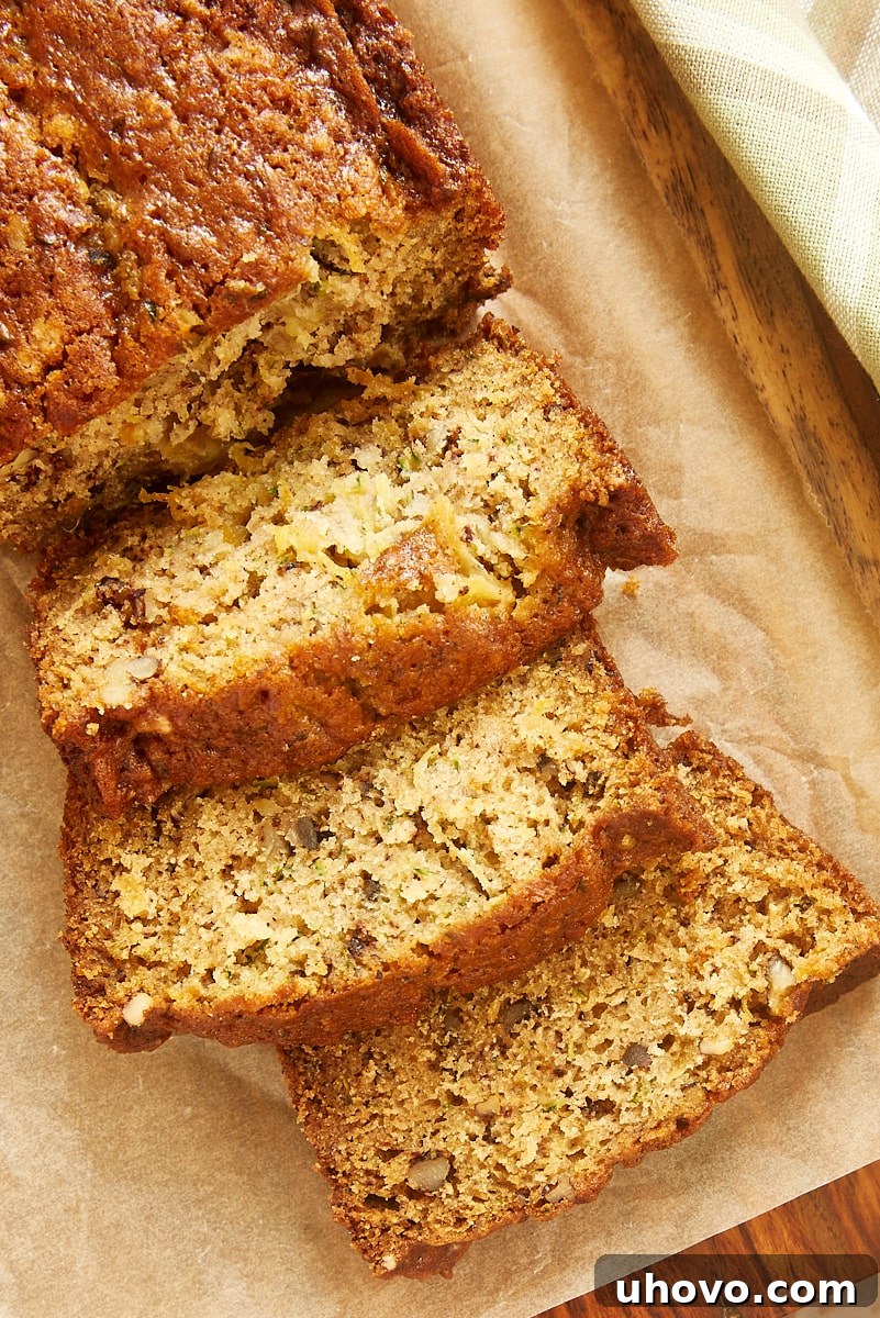 Overhead view of several slices of Pineapple Zucchini Bread arranged neatly on a wooden cutting board, showcasing the delicious texture and visible flecks of zucchini and pineapple.