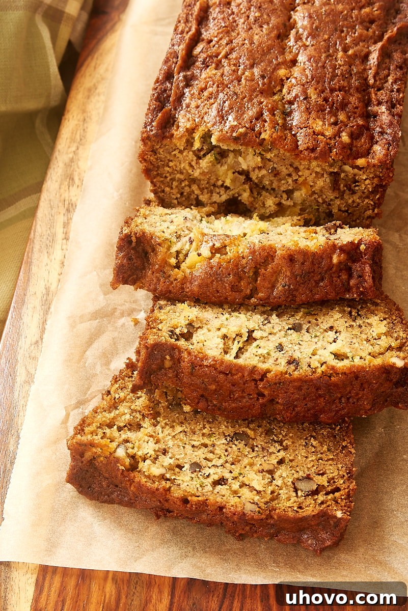 A close-up of a single slice of Pineapple Zucchini Bread, showing its moist crumb, visible bits of zucchini and pineapple, and crunchy nuts.