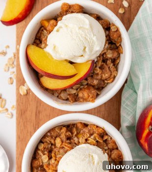 overhead view of peach crisp for two in white bowls set on top of a wooden board