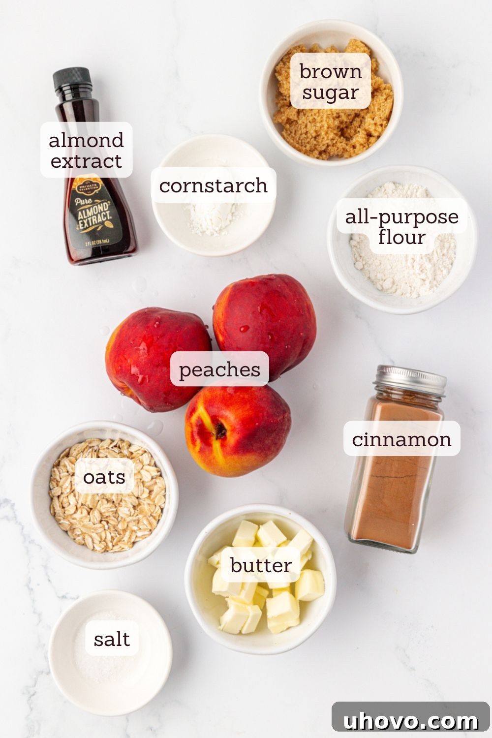 An overhead view of the key ingredients for small-batch peach crisp laid out on a wooden surface, including fresh peaches, oats, flour, brown sugar, butter, and spices, ready for preparation.