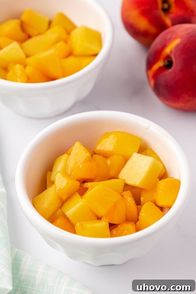 An overhead shot showing the vibrant peach crisp filling evenly divided into two elegant white ramekins, ready for the topping and baking process.