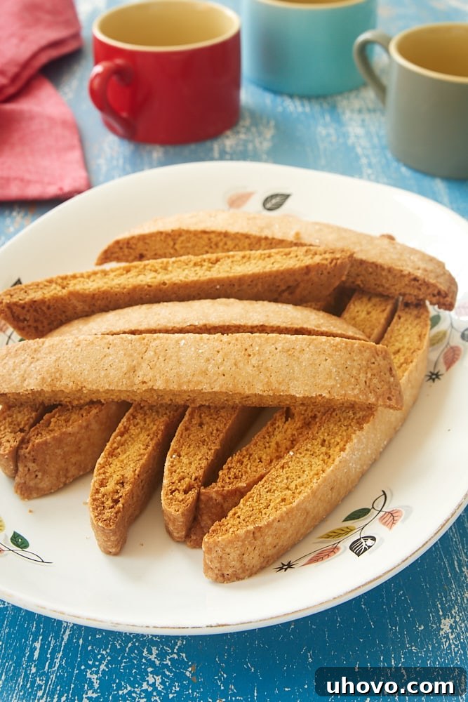 Easy Vanilla Biscotti stacked on a white plate with a floral rim, ready to be enjoyed.