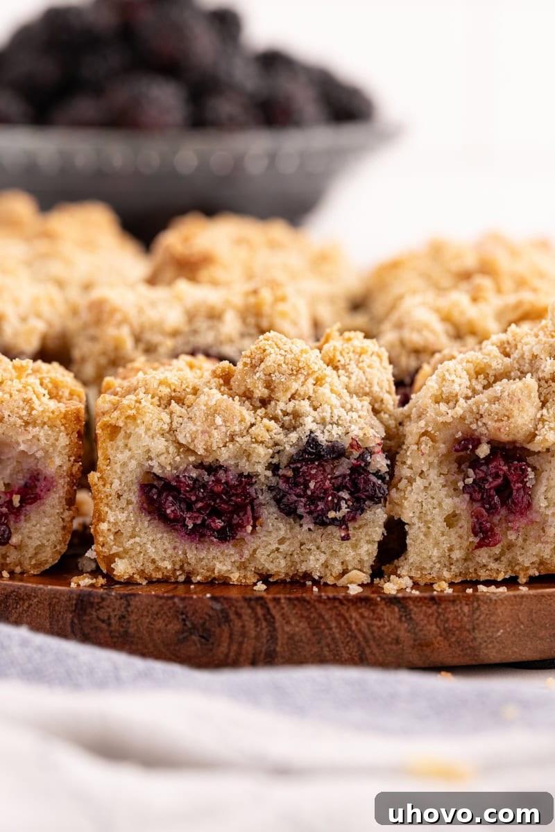 Freshly baked blackberry crumb bars artfully arranged on a rustic wooden cutting board, highlighting their golden-brown crumb topping and juicy berry filling, ready to be served.