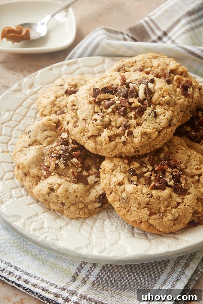 A stack of golden-brown Cookie Butter-Stuffed Oatmeal Cookies on a white plate, showcasing their generous size and inviting texture.