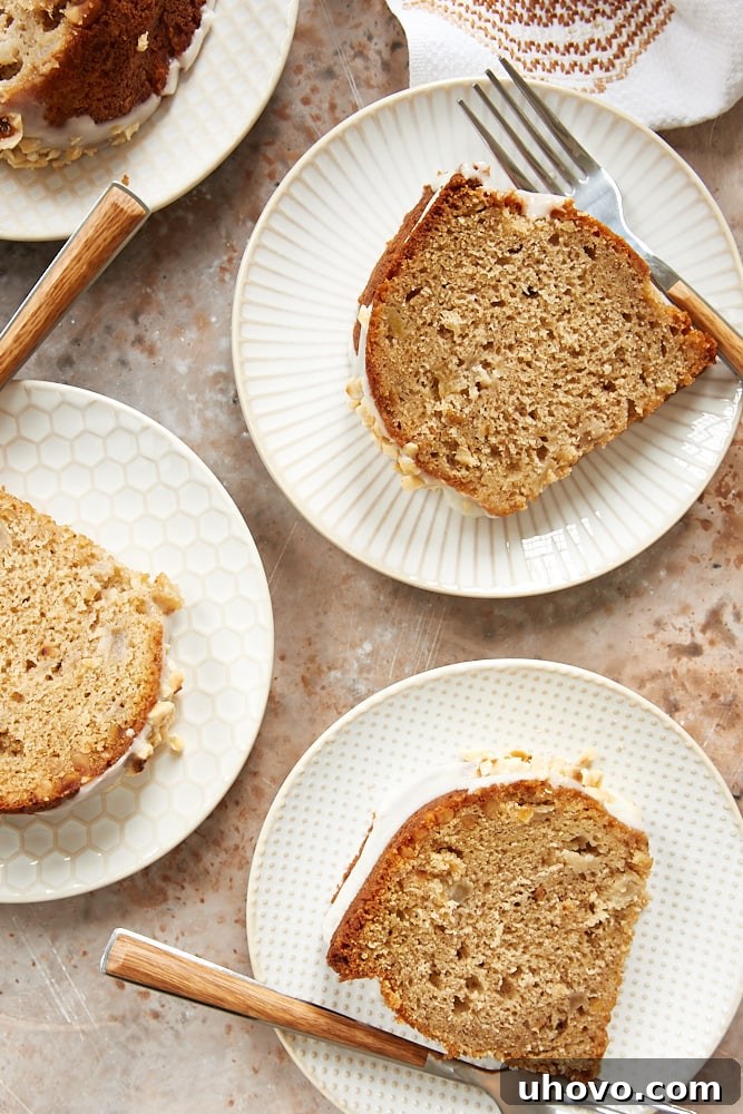 Several slices of Hazelnut Pear Bundt Cake arranged artfully on a serving plate, highlighting the dense, moist texture and visible pieces of pear and hazelnut, all gleaming under a light sour cream glaze.