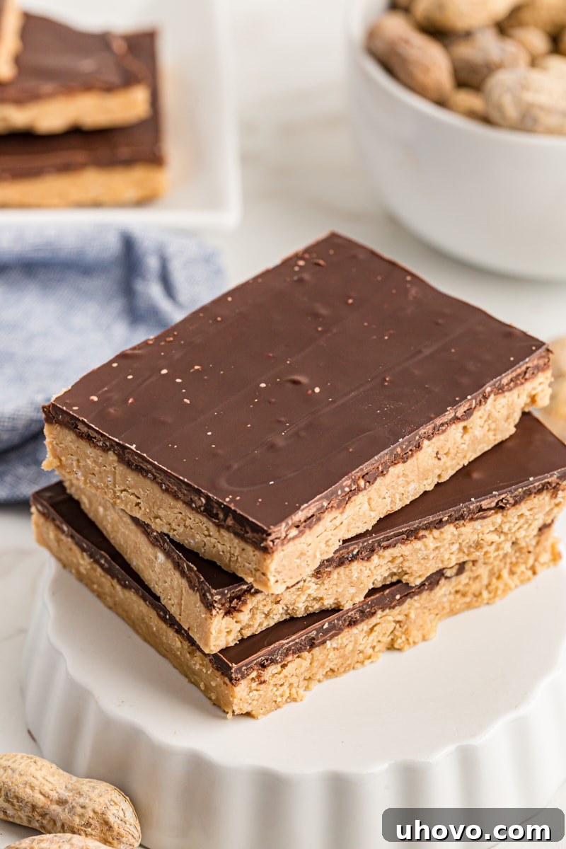 A perfectly stacked trio of rich No-Bake Peanut Butter Chocolate Bars resting elegantly on an upside-down tart pan, showcasing their tempting layers.
