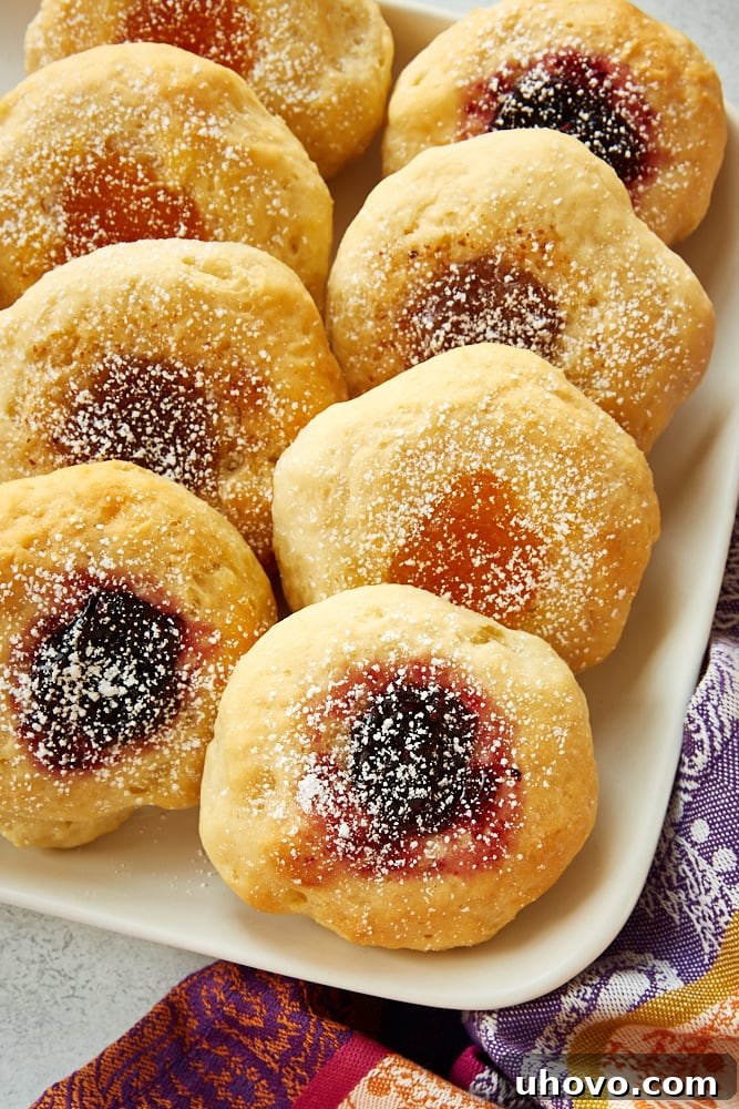 Freshly baked kolaches dusted with powdered sugar on a pristine white serving tray