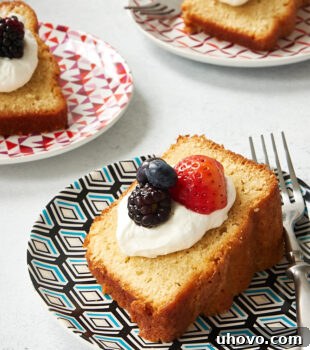 A beautiful slice of Sour Cream Pound Cake, elegantly garnished with sweetened whipped cream and fresh mixed berries.