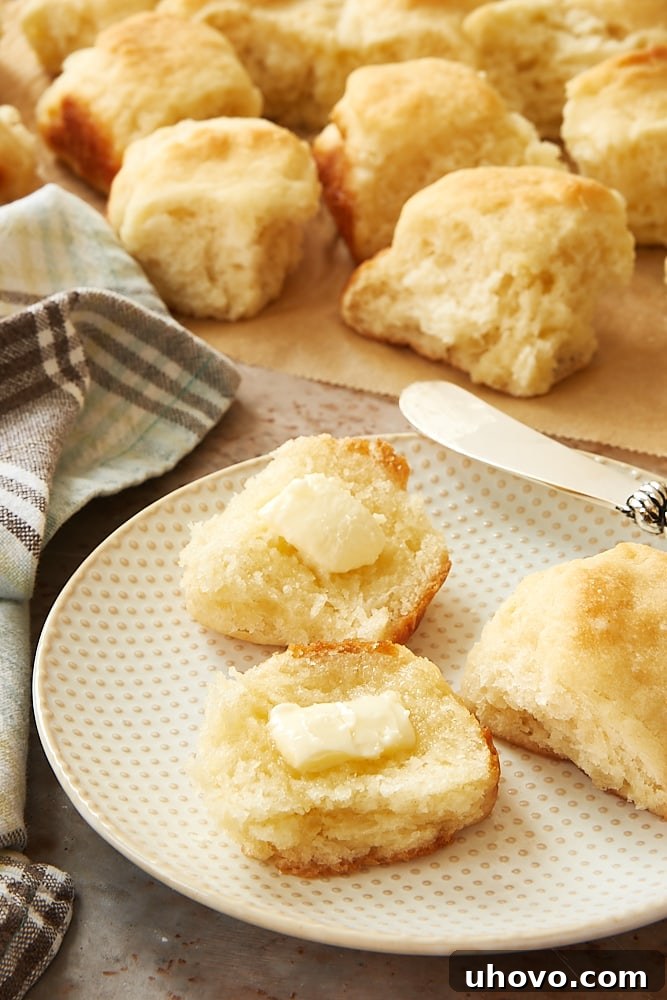 Two Angel Biscuits split apart and generously spread with melting butter, ready to be enjoyed.