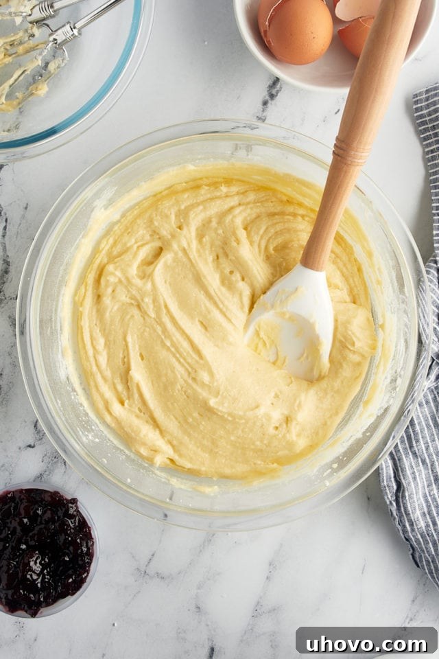Overhead view of the fully mixed Black Cherry Sour Cream Coffee Cake batter in a glass mixing bowl, smooth and ready for assembly.