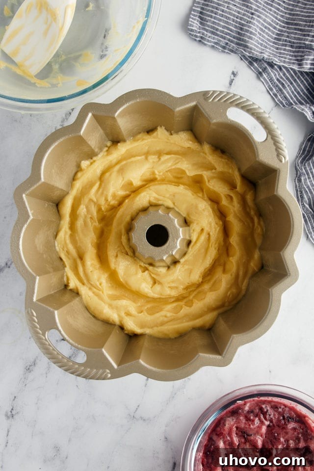 The Black Cherry Sour Cream Coffee Cake batter carefully placed in a Bundt pan with a distinct trough made in the center, ready for the cherry filling.
