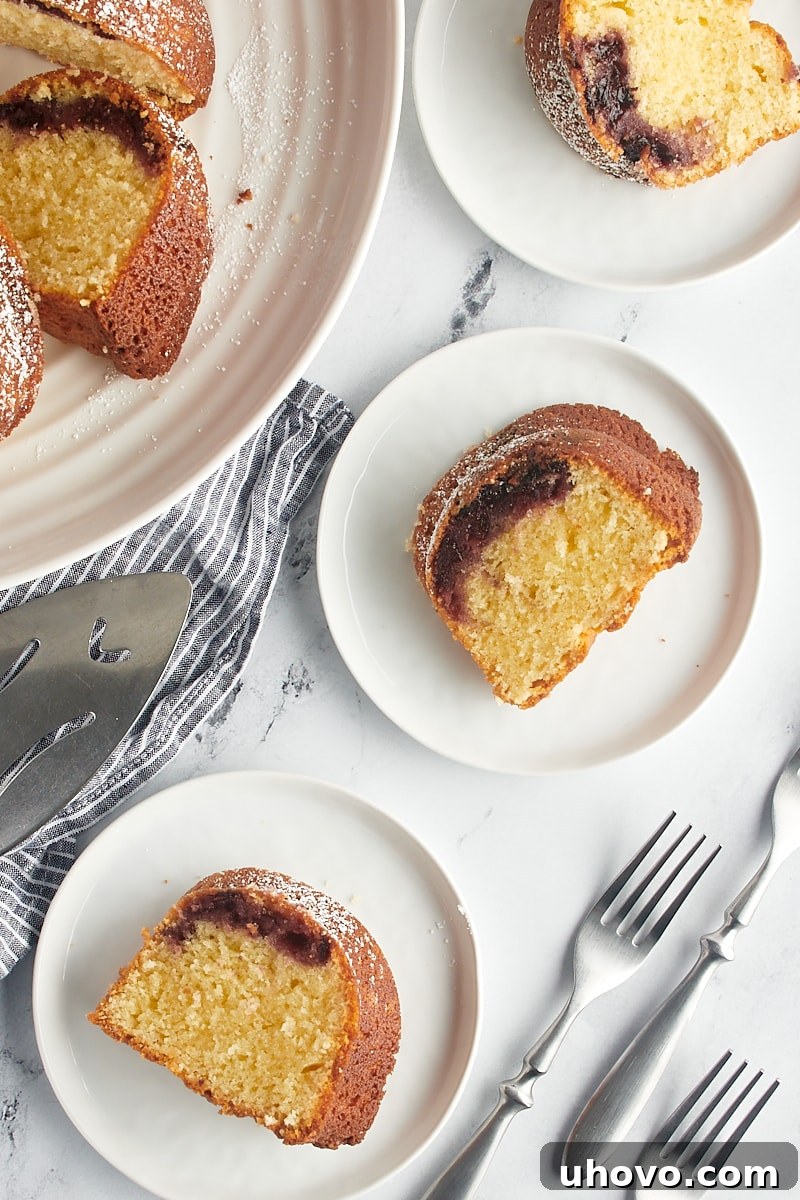 A charming overhead view of several slices of Black Cherry Sour Cream Coffee Cake artfully arranged on white plates, ready to be enjoyed.