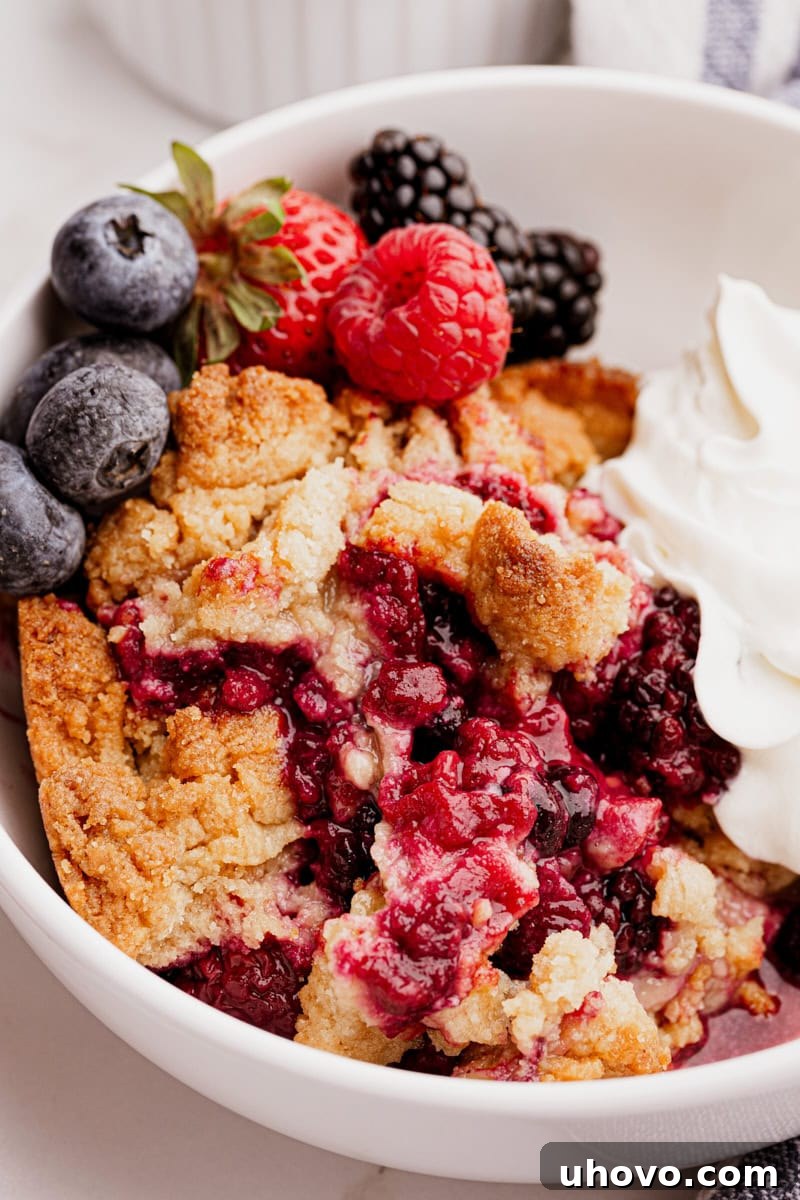 A delectable mixed berry cobbler served in a rustic bowl, adorned with a swirl of fresh whipped cream and a few scattered fresh berries.