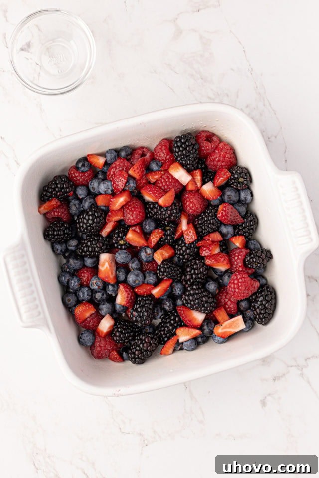 A vibrant assortment of fresh berries artfully arranged in a baking dish, glistening with a hint of lemon juice.