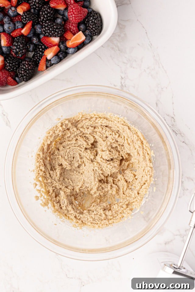 Close-up of a bowl where softened butter, brown sugar, and vanilla extract are being creamed together for the rich cobbler topping.