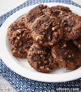 Flourless Chocolate Hazelnut Cookies piled on a white plate on a blue and white napkin