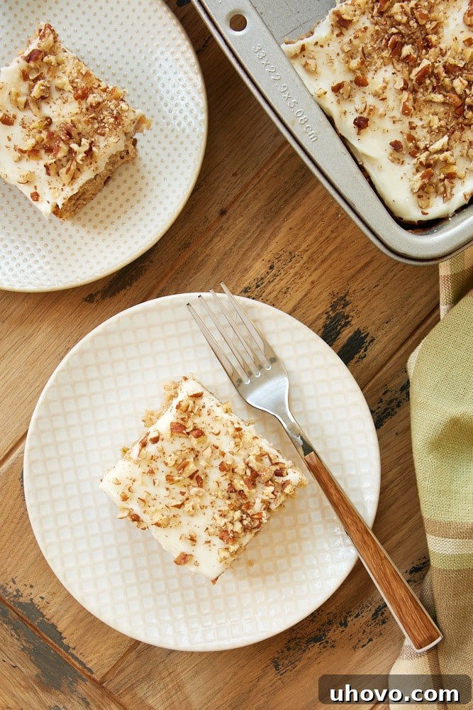 Overhead view of several Frosted Zucchini Bars arranged neatly on white and beige plates, showcasing their rich frosting and chopped nut topping.