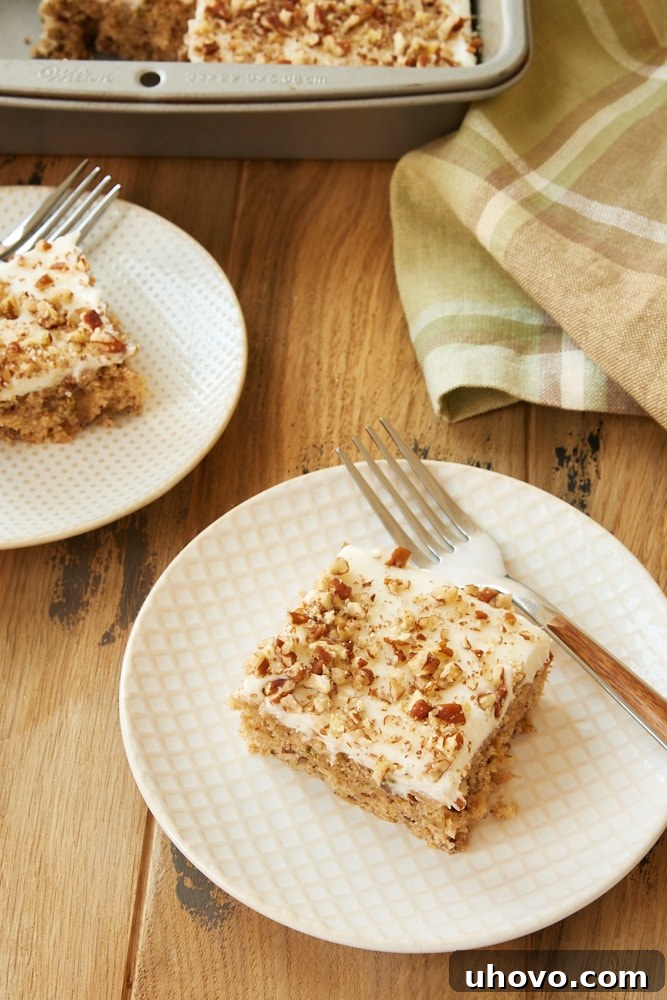 Close-up shot of Frosted Zucchini Bars, highlighting the creamy frosting, chopped nuts, and moist cake texture, served on decorative plates.