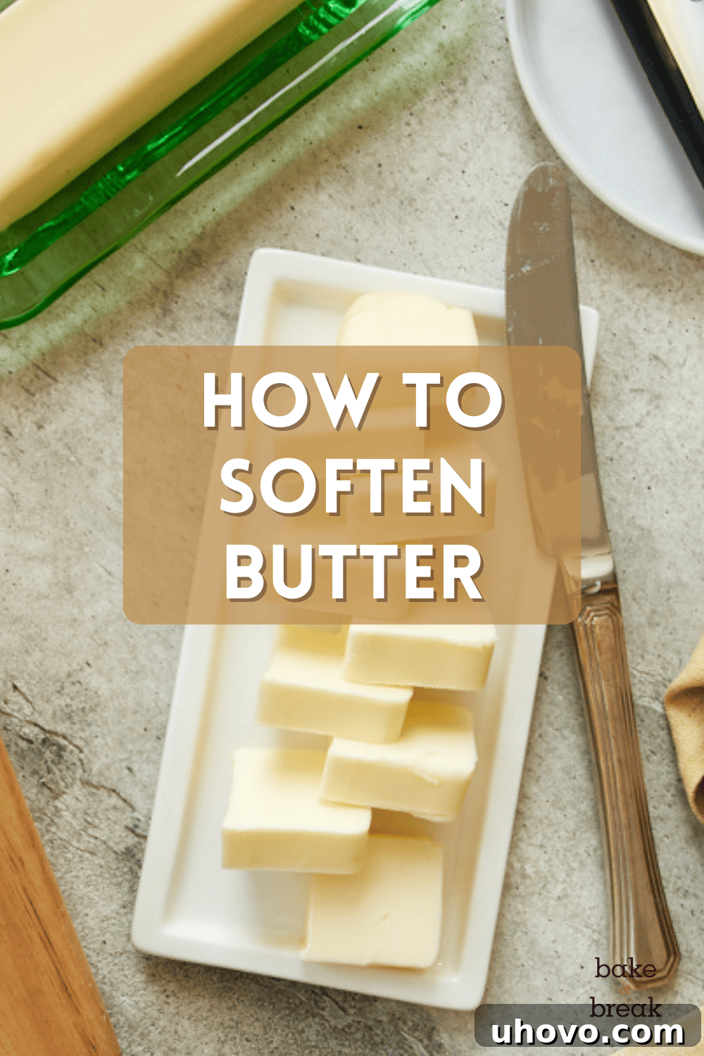 How to Soften Butter for Baking: A stick of butter with a thumbprint indent, indicating perfect softness. It sits on a kitchen counter next to a whisk and a bowl.