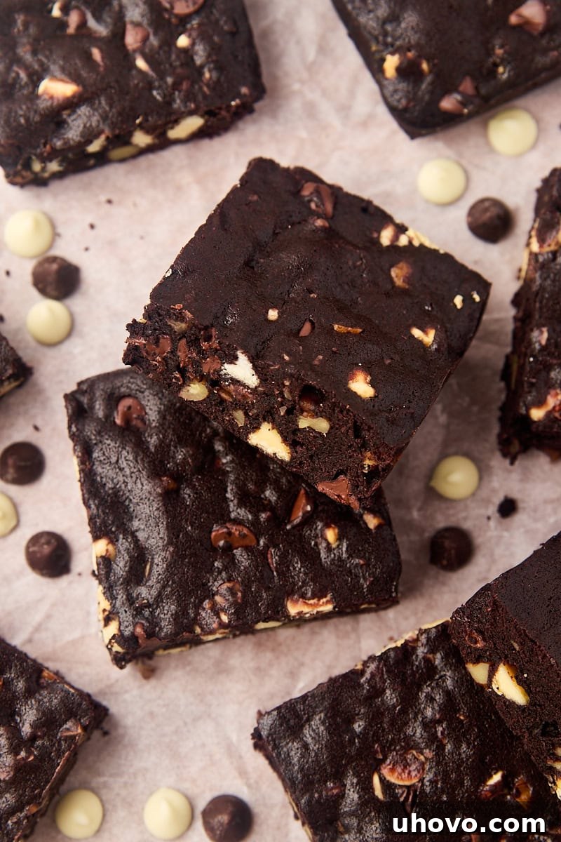 Triple chocolate brownies on parchment paper, showcasing their rich, fudgy texture and a medley of chocolate chips