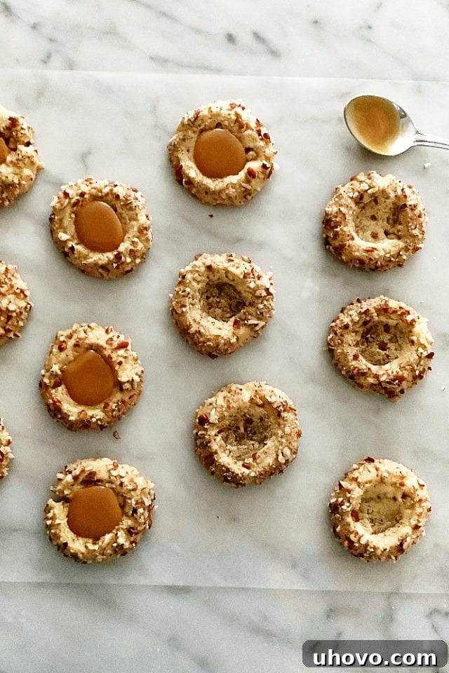 overhead view of pecan thumbprint cookies, some filled with caramel