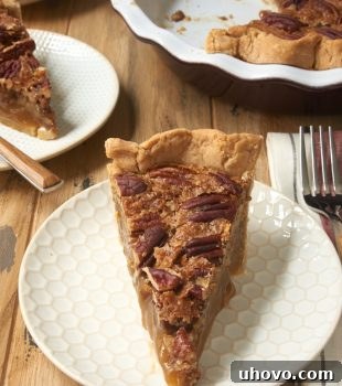 slice of Irish Cream Pecan Pie on a white and beige plate