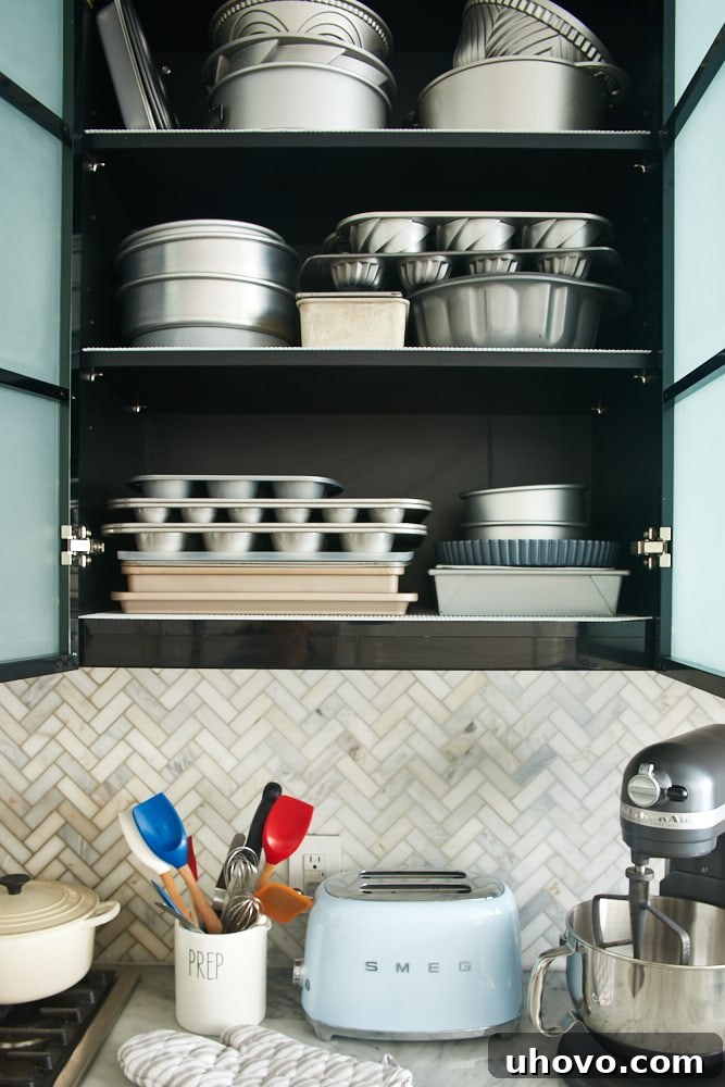 Organized baking pans neatly stacked in a kitchen cabinet, showcasing efficient vertical storage.