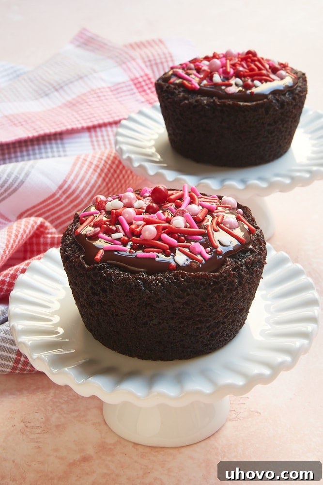 Two decadent Chocolate Cupcakes for Two served elegantly on small white cake stands, ready for a sweet indulgence