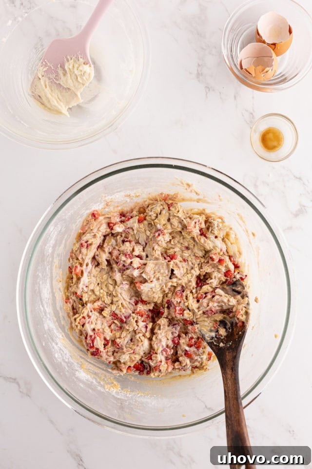 Overhead view of the strawberry cream cheese bread batter in a glass mixing bowl, showing beautiful streaks of the cream cheese swirl after a few turns of mixing.
