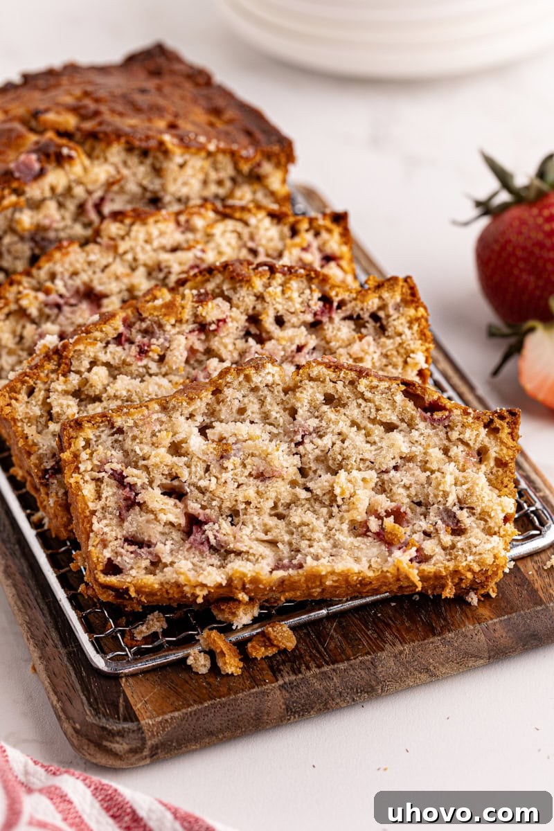 Close-up view of beautifully sliced Strawberry Cream Cheese Bread on a wooden cutting board, revealing the tender crumb and distinct cream cheese swirl.