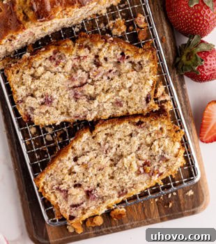 Overhead view of several slices of Strawberry Cream Cheese Bread on a wooden cutting board, showcasing the vibrant strawberries and creamy swirl.