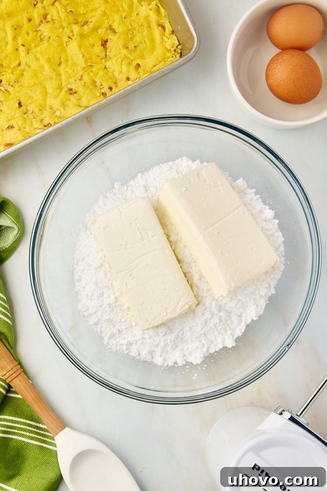 overhead view of cream cheese and confectioners' sugar in a glass mixing bowl