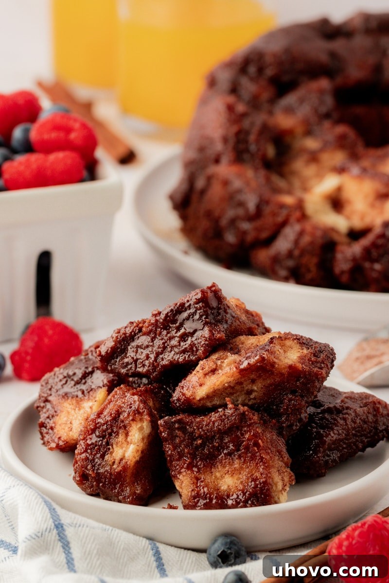 A plate of freshly baked chocolate monkey bread with remaining bread in a Bundt pan in the background, showcasing its delicious, pull-apart layers.