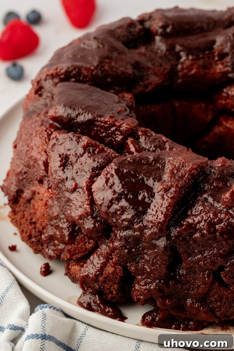 A glorious chocolate monkey bread sitting on a serving platter, glistening with its sticky chocolate-cinnamon glaze, ready to be enjoyed.