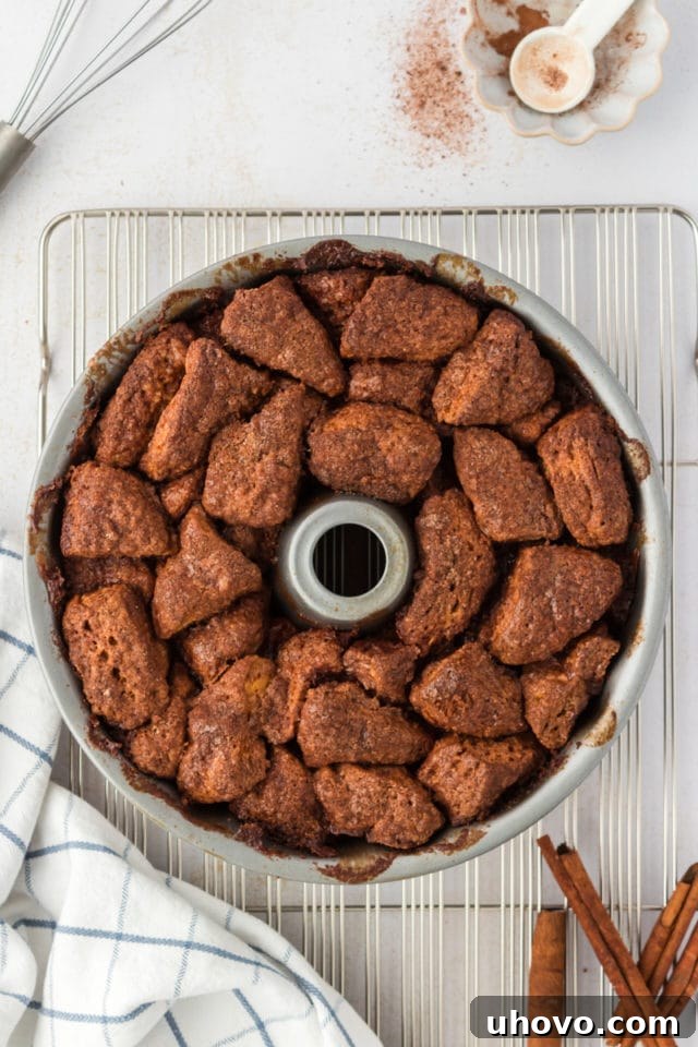 Overhead view of the freshly baked chocolate monkey bread still in its Bundt pan, resting on a wire cooling rack, showcasing its golden-brown crust and bubbling, sticky glaze.