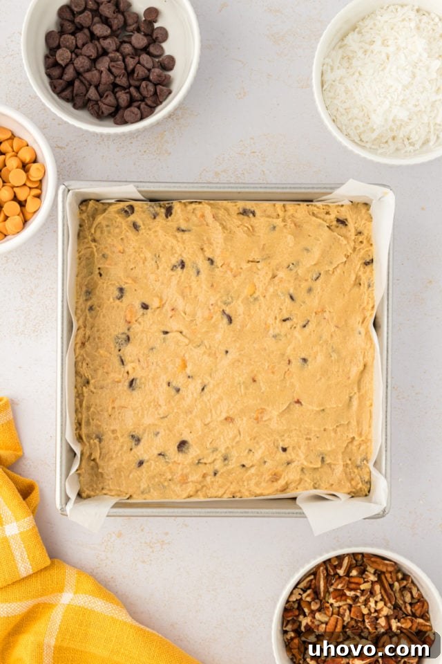 An overhead view of the rich toffee squares dough carefully spread evenly across the bottom of a rectangular baking pan, ready for toppings.