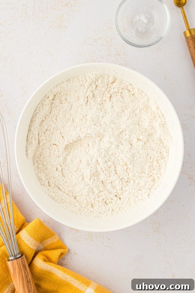 An overhead view of the dry ingredients for toffee squares—flour, baking soda, and salt—perfectly mixed in a white bowl.