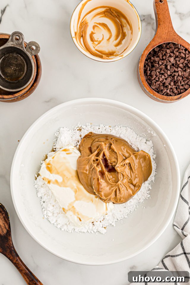 Overhead view of peanut butter, vanilla, cream cheese, and sugar in mixing bowl