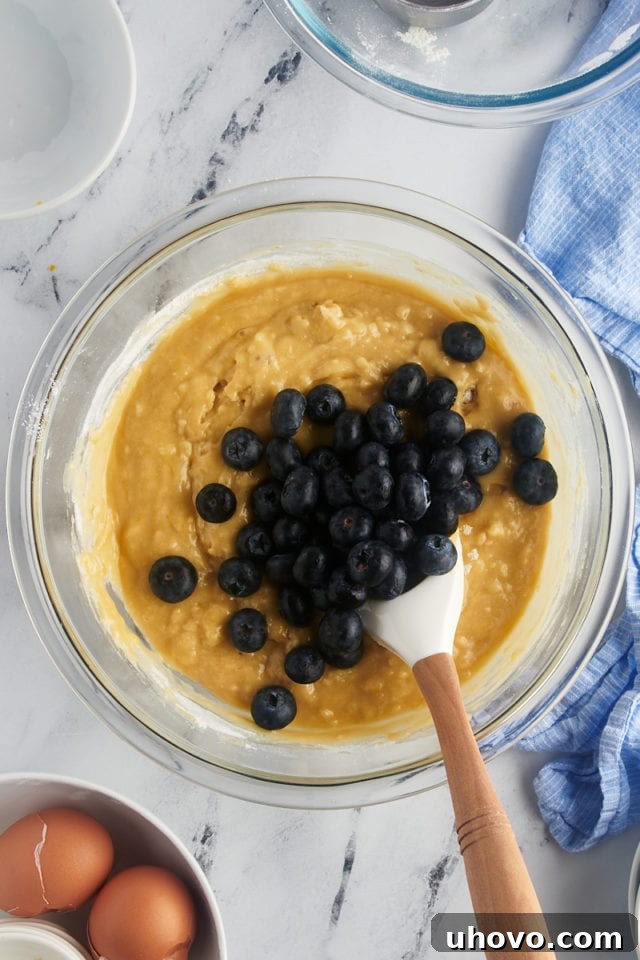 Overhead view of blueberries added to bowl of batter
