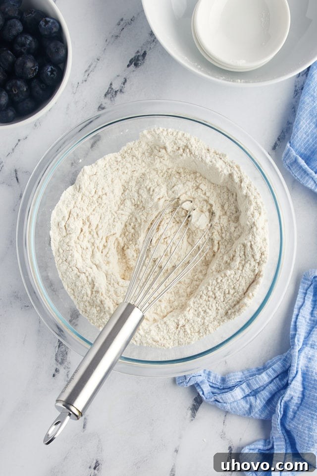 Overhead view of dry ingredients in glass bowl with whisk
