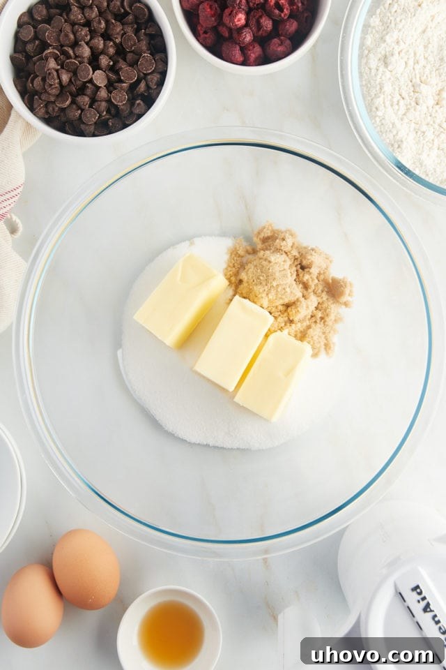 Softened unsalted butter, granulated sugar, and light brown sugar being creamed together in a mixing bowl.