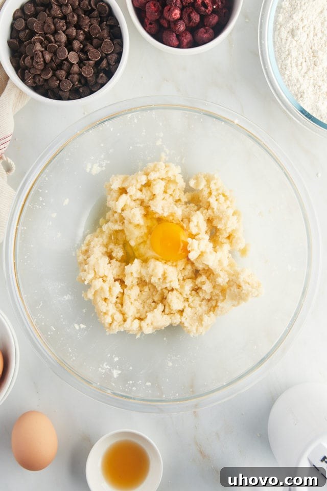 Room temperature eggs being added one by one to the creamed butter and sugar mixture.