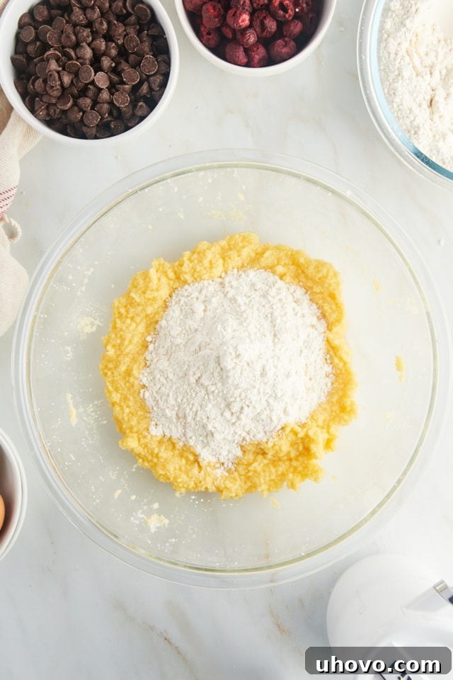 The whisked dry flour mixture being gradually added to the wet butter and sugar mixture in a large mixing bowl.