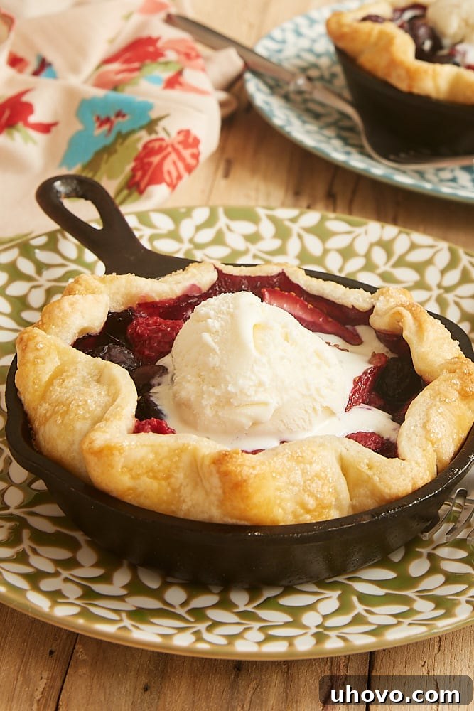 Two adorable mini skillet mixed berry pies, fresh from the oven, with a lattice crust.