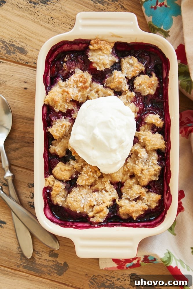 A mixed berry cream cheese crisp served in a small dish, with a golden-brown topping and juicy berries peeking through.