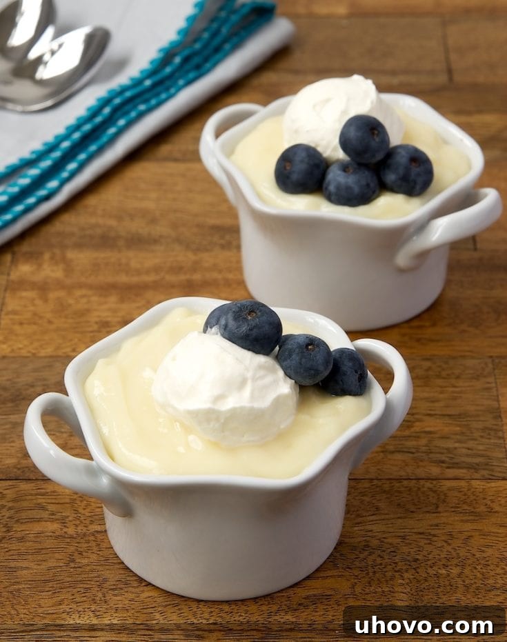 Individual servings of homemade Vanilla Pudding, garnished with fresh berries and a sprig of mint.