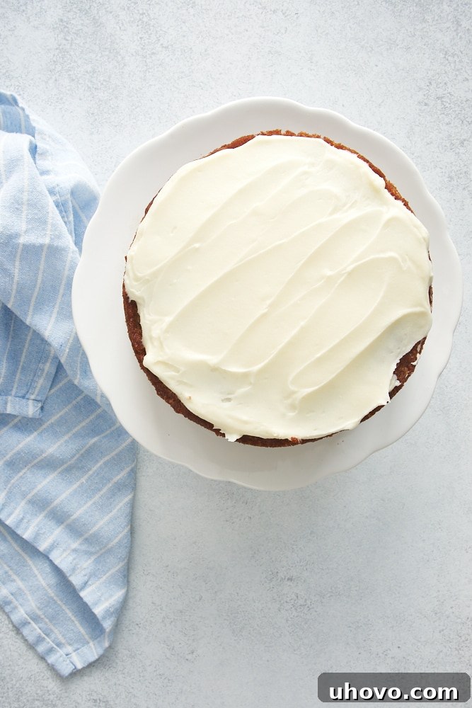 Overhead perspective of a partially frosted 6-Inch Hummingbird Cake, with one layer already covered in a smooth layer of cream cheese frosting.