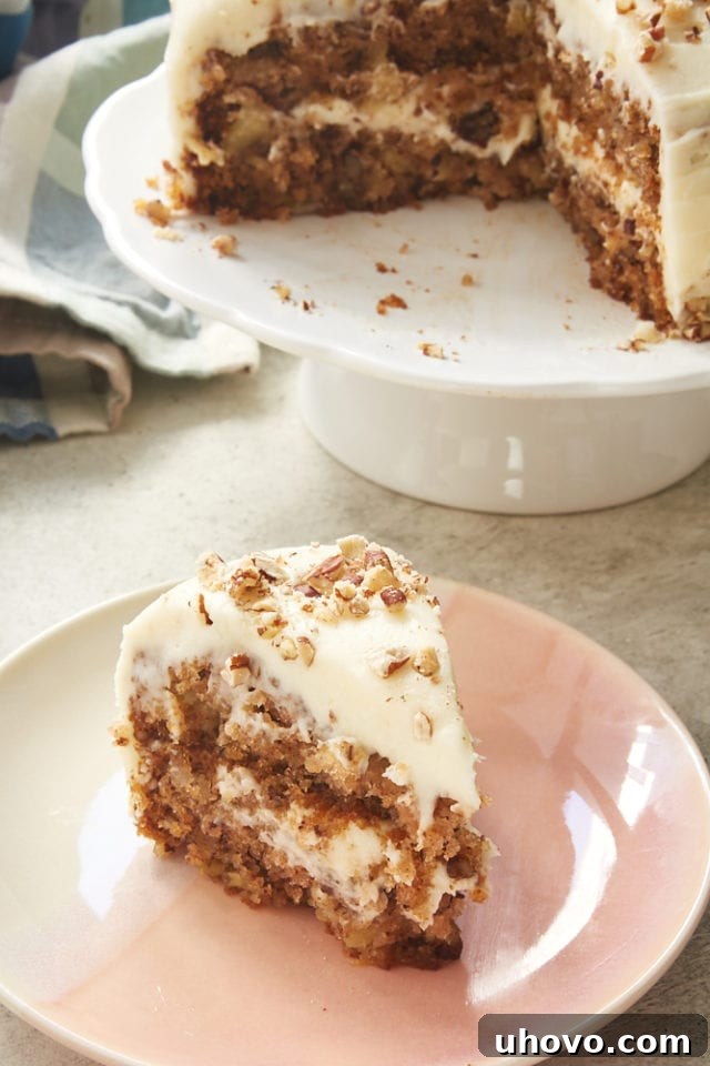 A perfectly sliced piece of 6-Inch Hummingbird Cake sits on a pink and white plate, revealing its moist layers and creamy frosting.